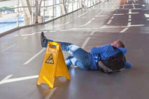 inattentive man has fallen down on wet floor in spite of the big yellow warning sign